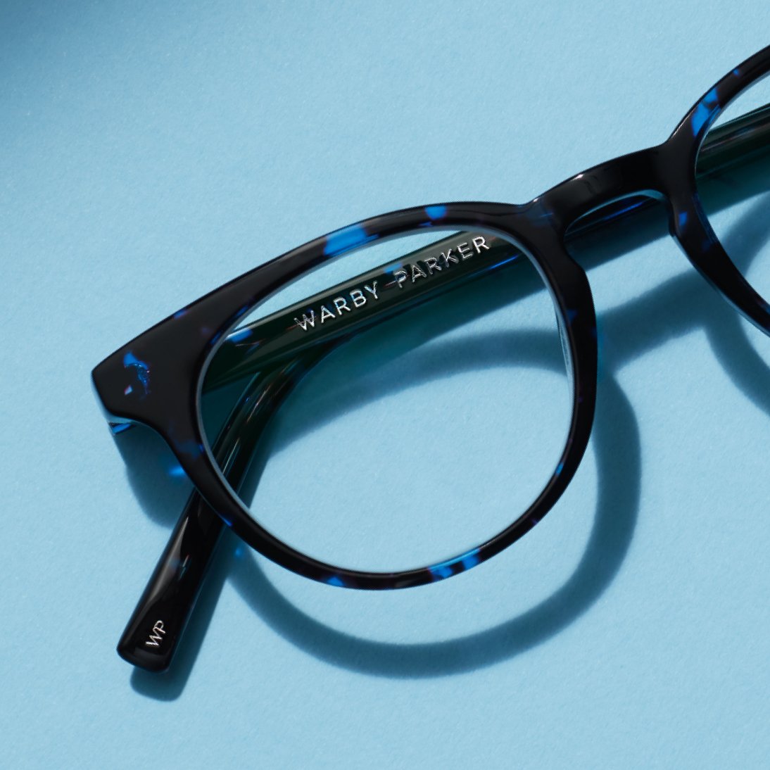 Close up view of a pair of blue and black Warby Parker glasses