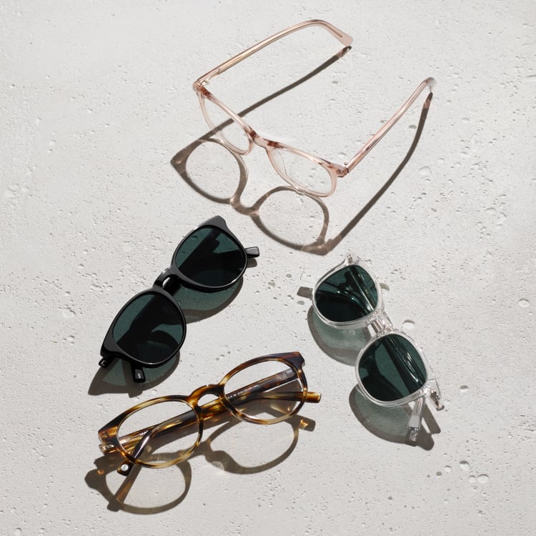 Four pairs of glasses on a light gray surface dappled with water droplets