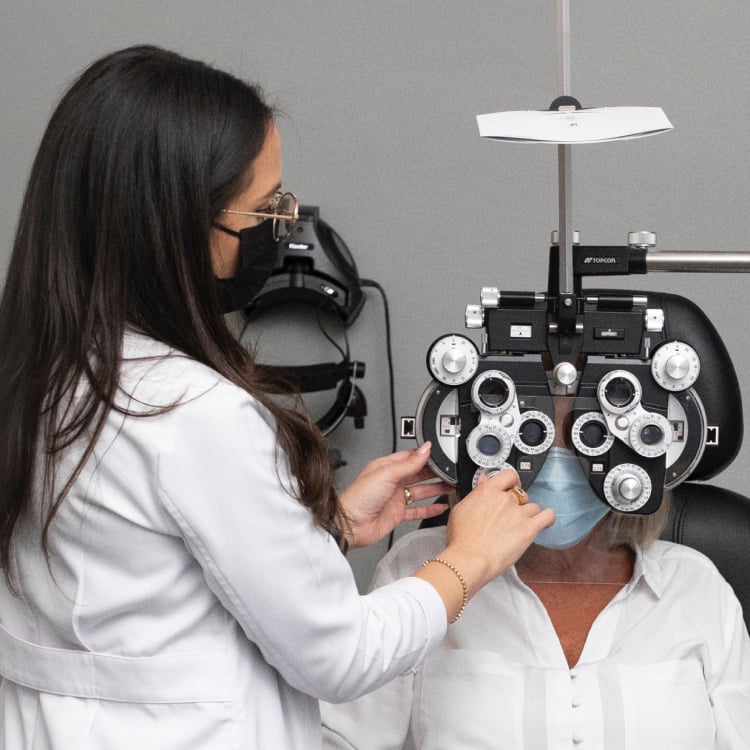 Optometrist adjusting a phoropter machine in front of a patient's eyes