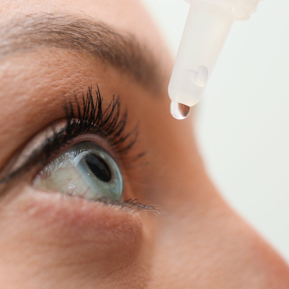 Close-up image of someone applying eye drops