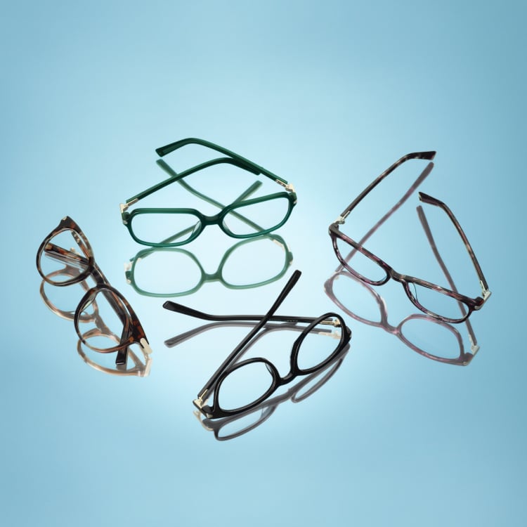 Four pairs of glasses casting shadows on a blue background