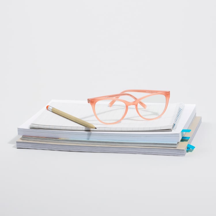 Orange glasses frames sitting on top of paperwork