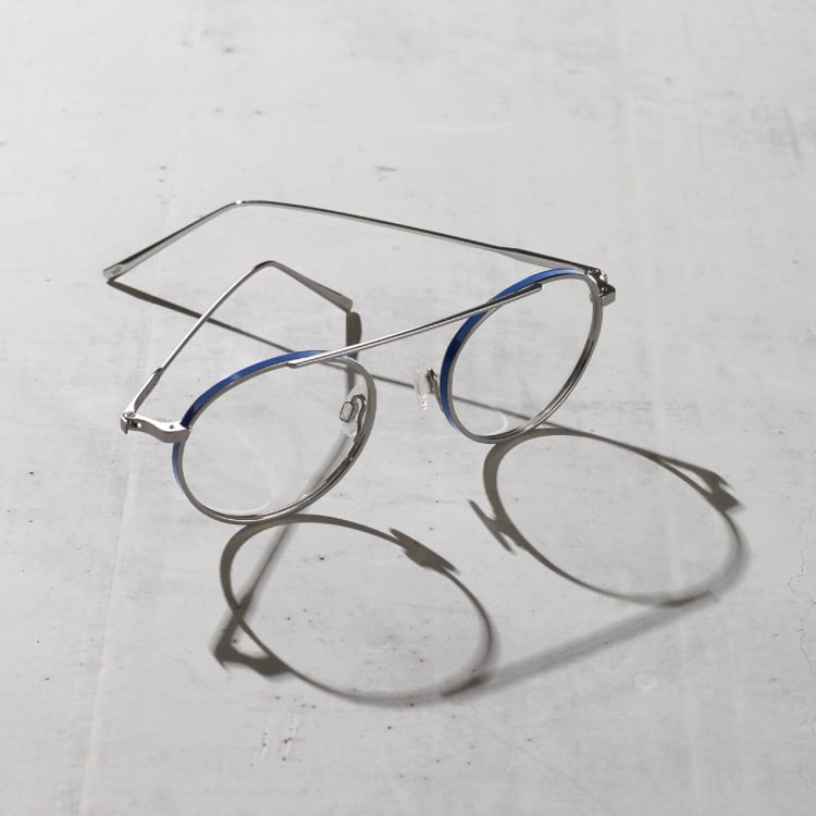 A pair of metal glasses frames sitting on concrete casting a shadow