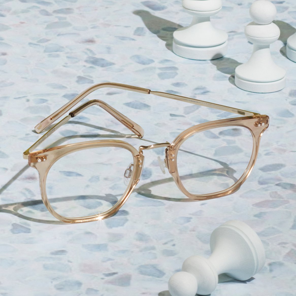 A pair of eyeglasses pictured with chess pieces on a light-colored surface