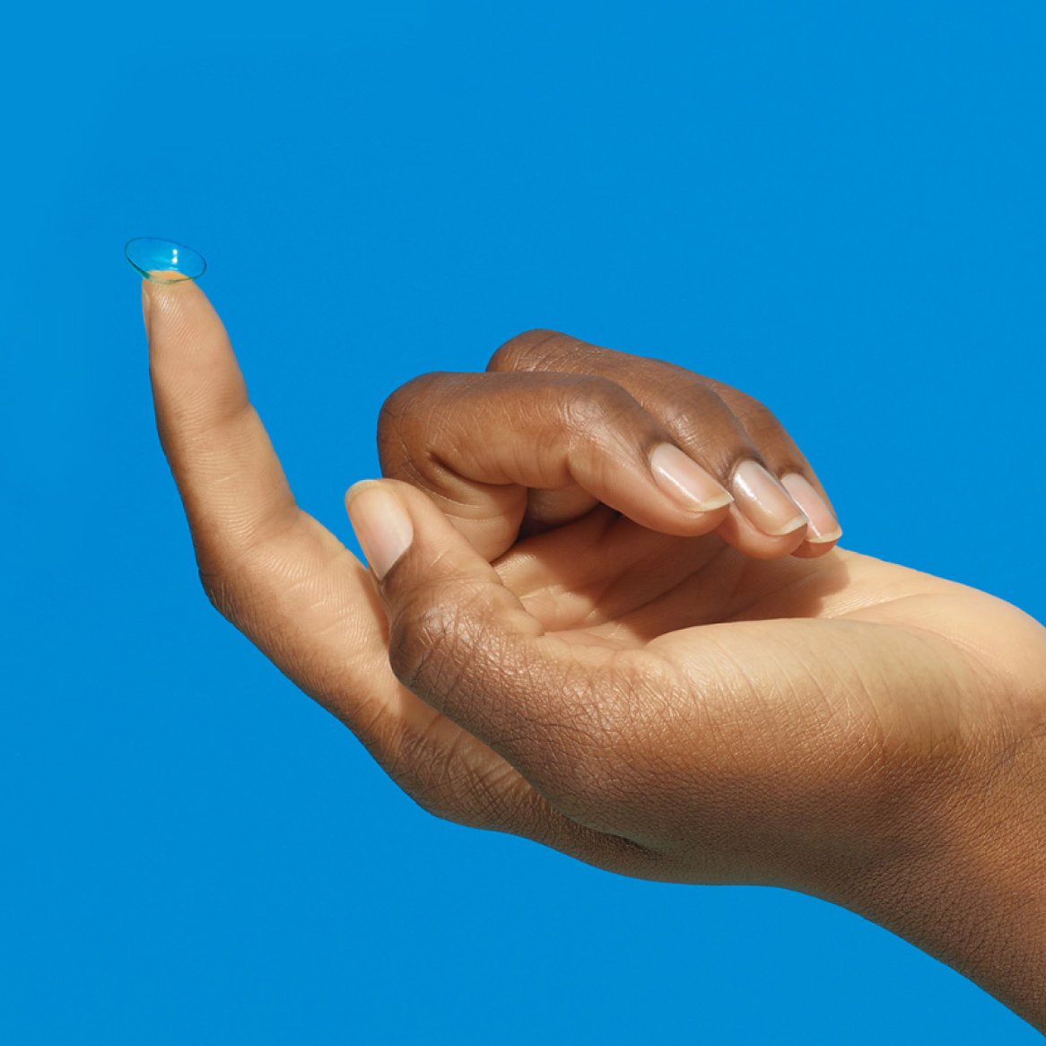 Image of a hand with contact lens on fingertip on a blue background